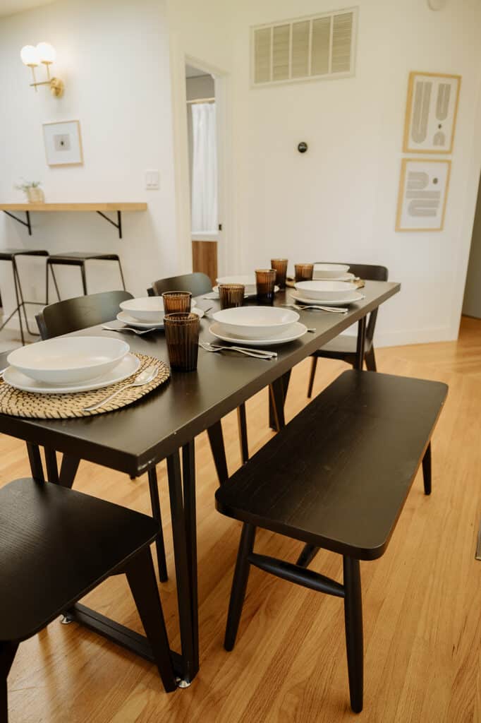 a dining table set with 6 settings and a bench