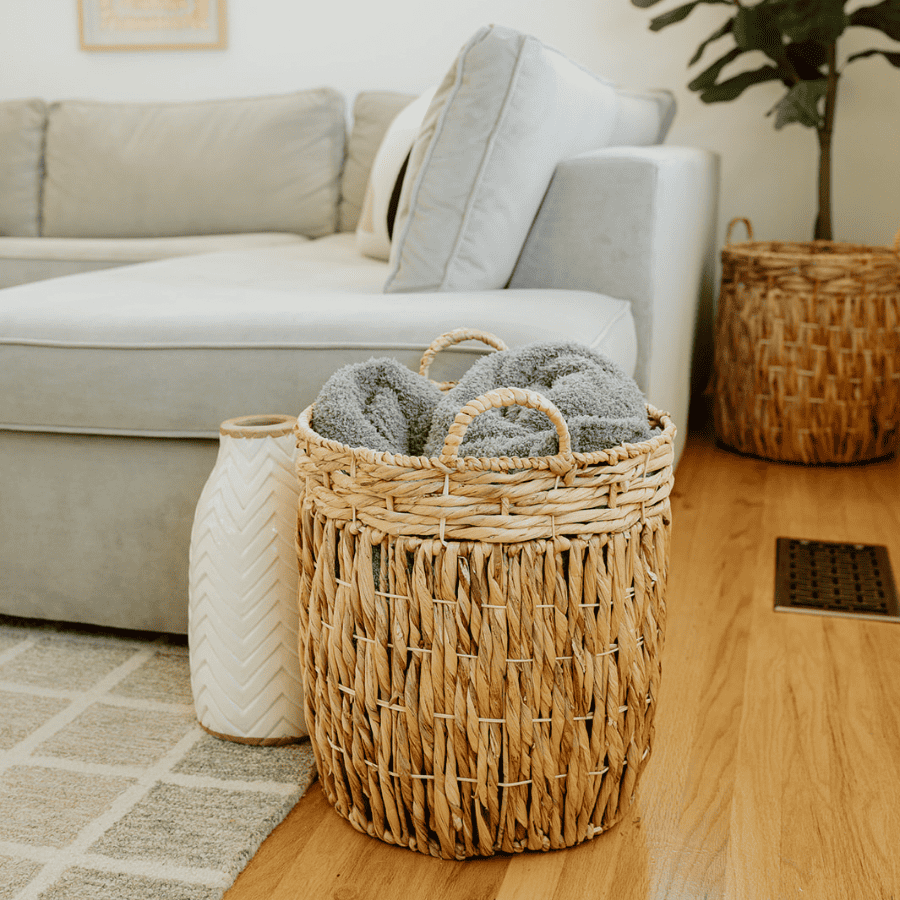 close up of a basket and vase at the foot of a sectional couch