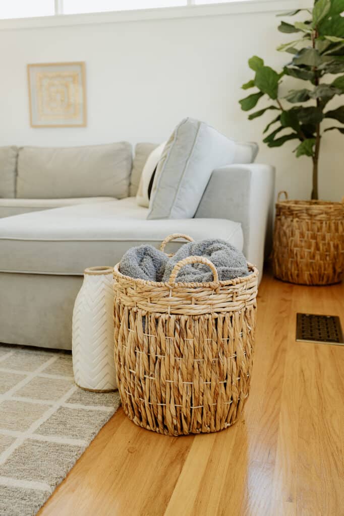 close up of a vase and blanket basket at the end of a sectional couch