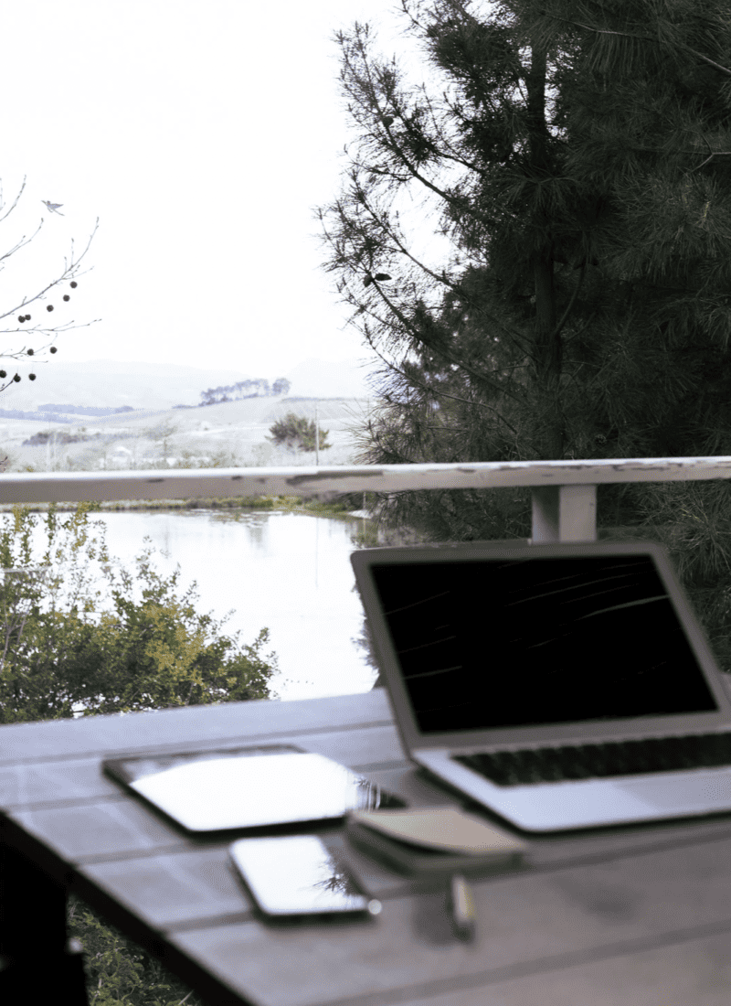 open laptop on an outdoor table overlooking a lake