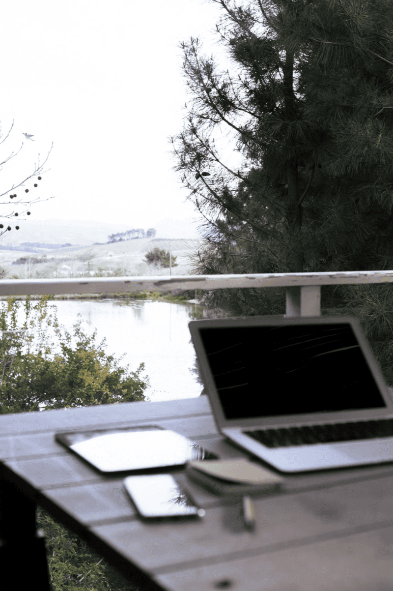 open laptop on an outdoor table overlooking a lake