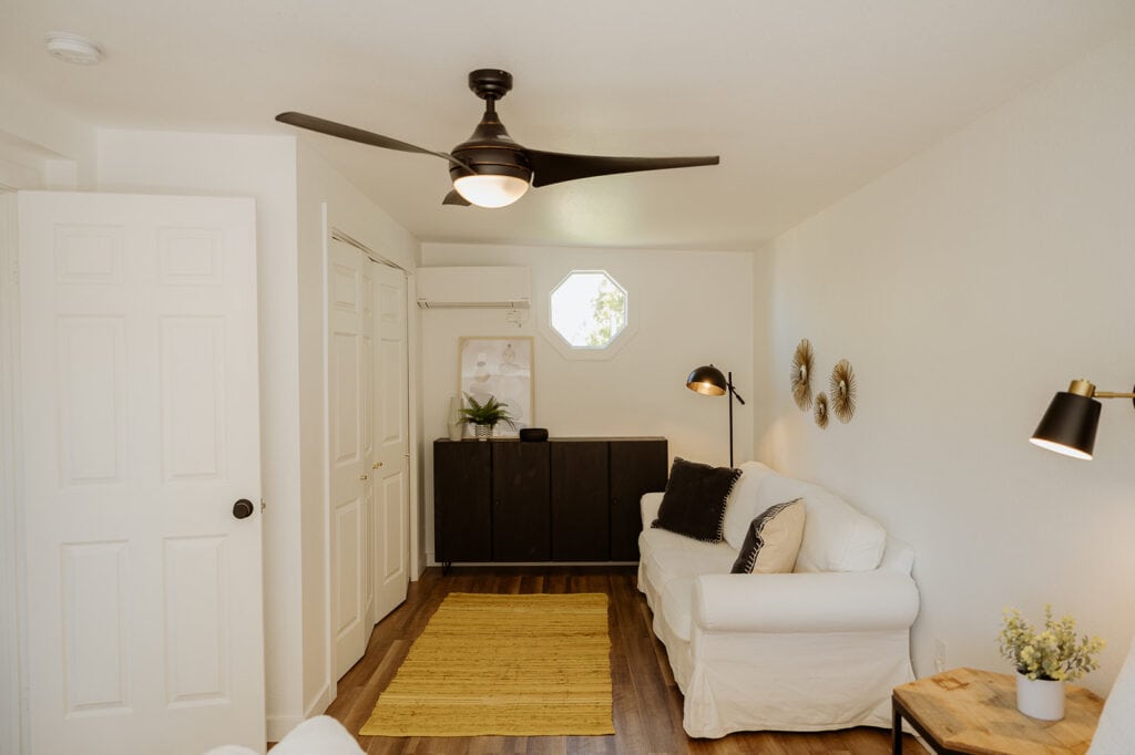 the corner of a bedroom that has a white couch and black sideboard